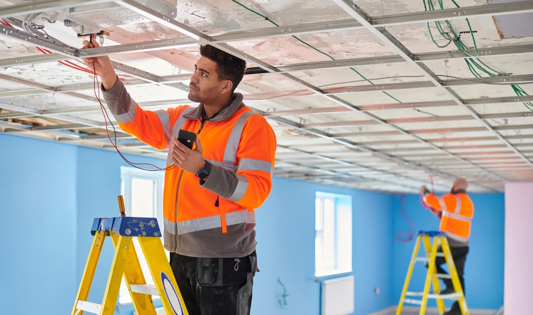 Electricians working on ceiling wiring